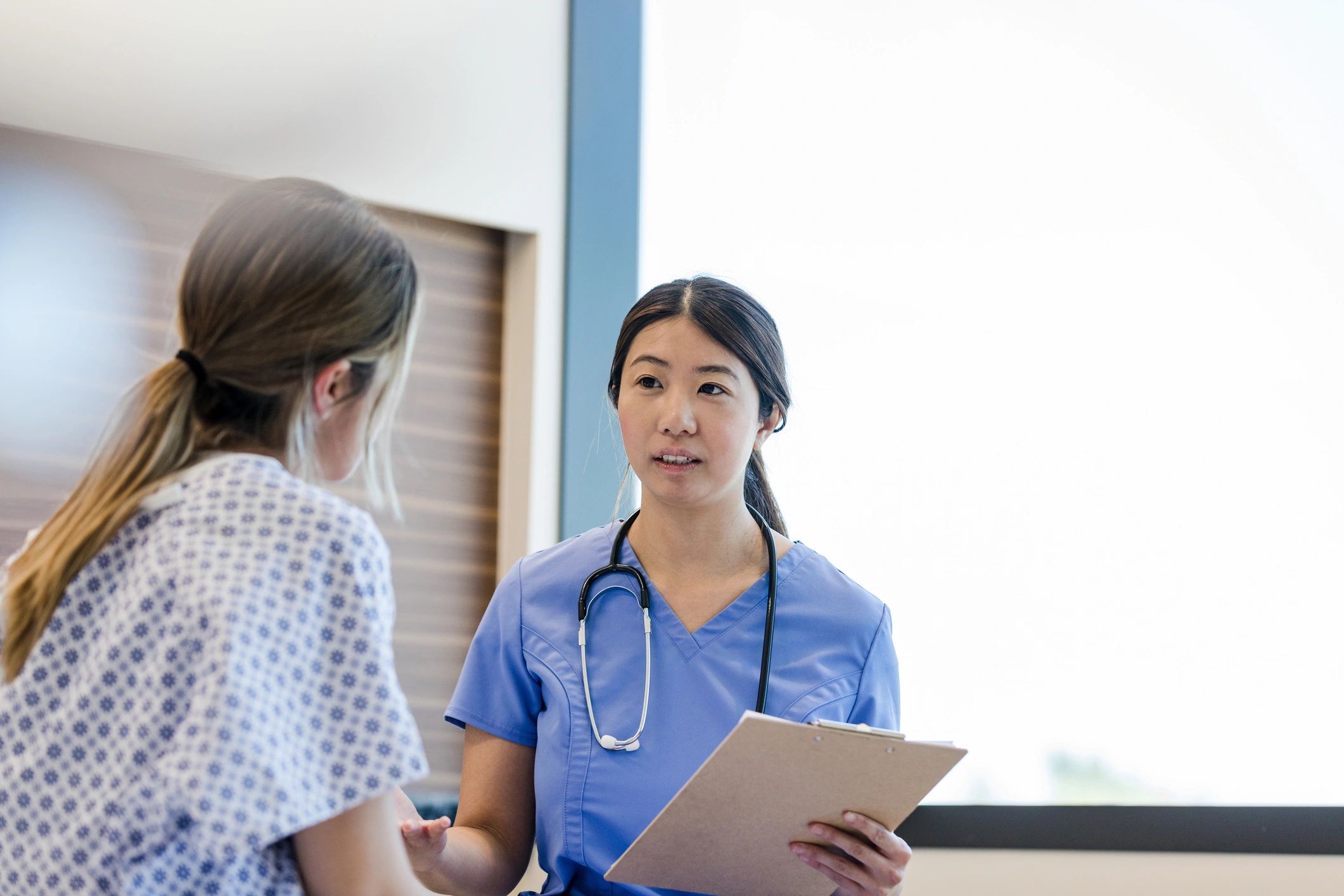 Nurse speaking with a patient in a hospital corridor